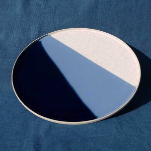 plat en céramique artisanal sur fond bleu. vue de dessus. Réalisé par graphiste en terre pour l'inatelier